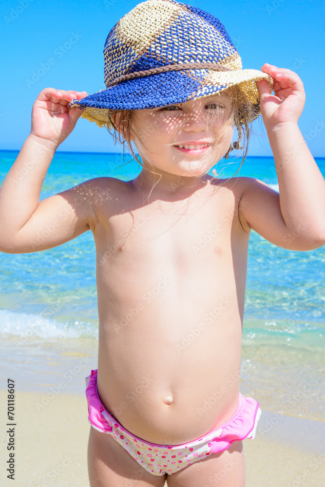 Bambina al mare con cappello azzurro