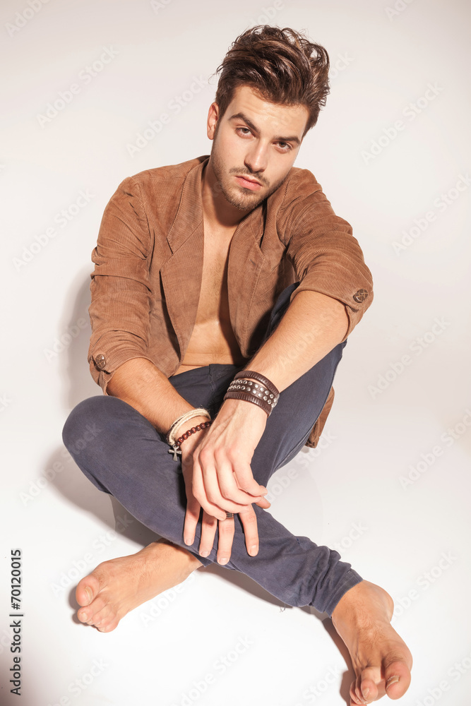 young man wearing a brown jacket sitting on the floor young man wearing a brown jacket sitting on the floor