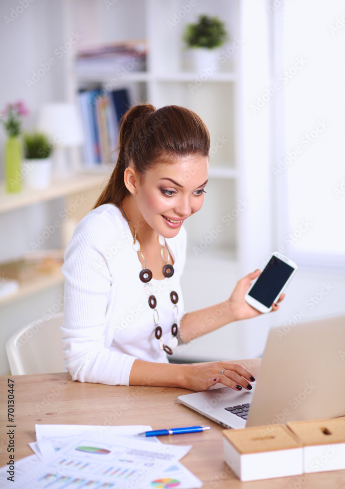 Young businesswoman sitting at the desk and talking on phone Young businesswoman sitting at the desk and talking on phone