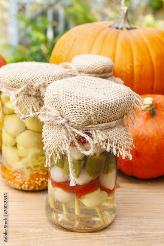 Pumpkins and colorful pickled vegetables in preserving glass photo