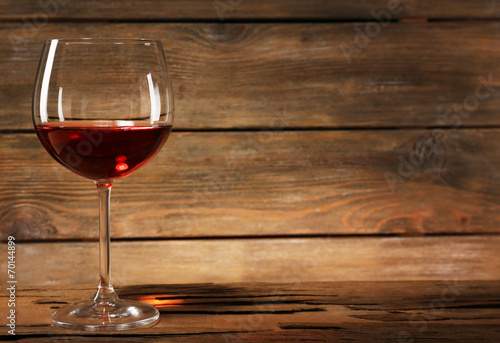 Goblet of red wine on wooden table on wooden wall background