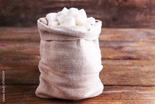 Refined sugar in bag on wooden background