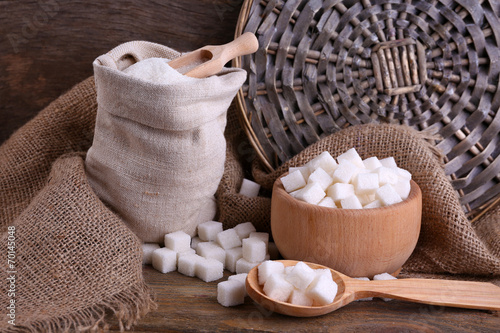 Refined sugar in bag and bowl on wooden background