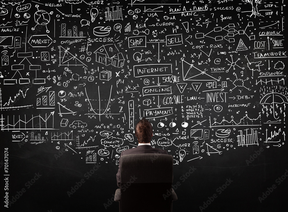 Businessman sitting in front of a blackboard with charts Businessman sitting in front of a blackboard with charts
