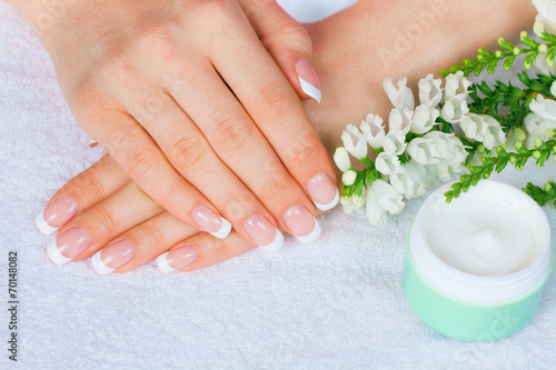 Female hands with french manicure near jar of cream