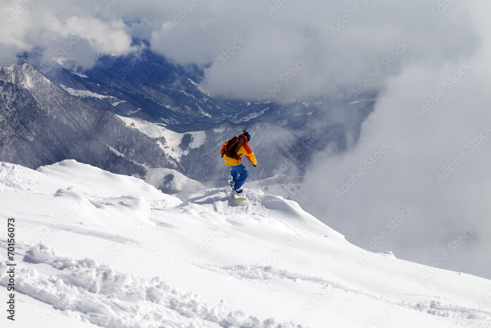 Snowboarder on off-piste slope an mountains in fog