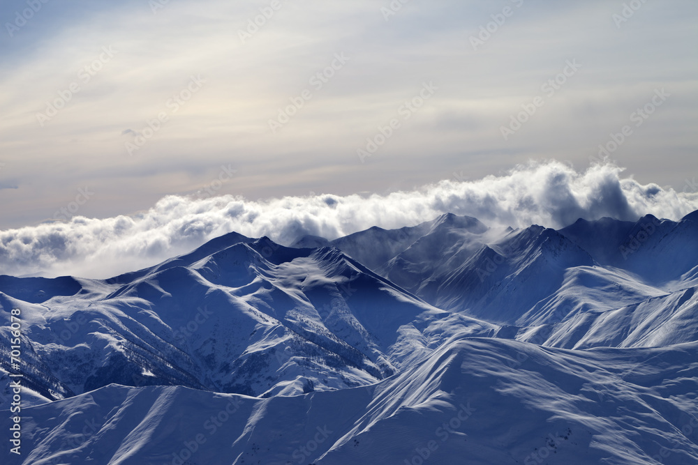 Fototapeta premium Snowy mountains in mist at winter evening