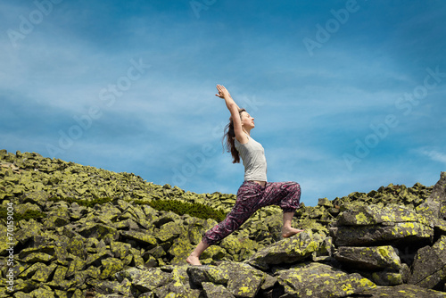 Woman doing yoga exercise on fresh air with blue sky on backgrou