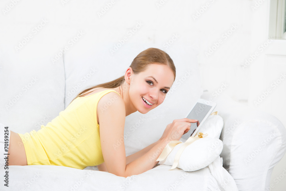 beautiful girl lying on the sofa and touching electronic tablet