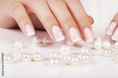 Beautiful woman's nails with french manicure and pearls.