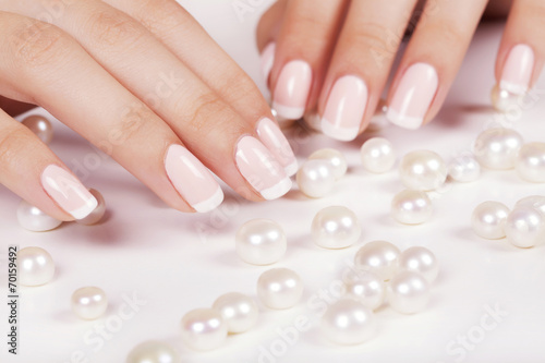 Beautiful woman s nails with french manicure and pearls.