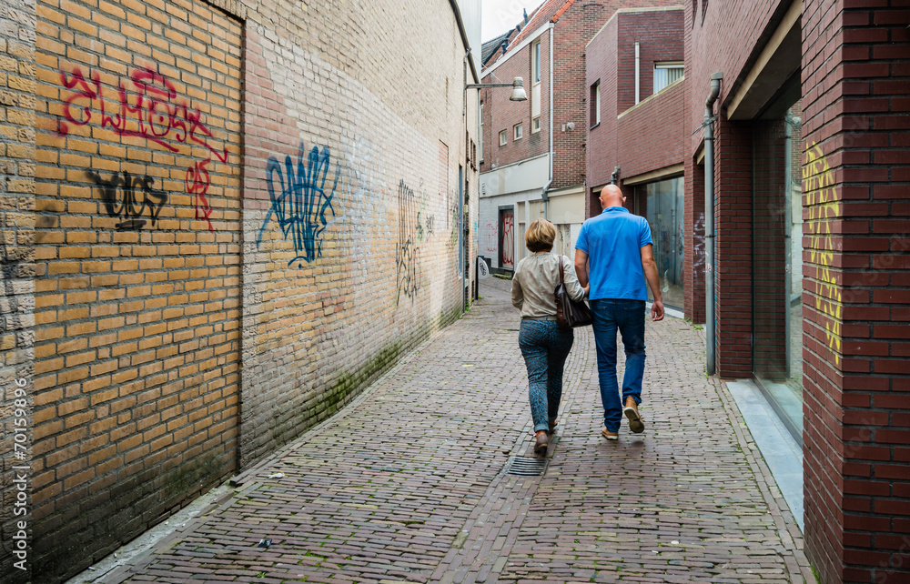 Man and woman walking through a narrow alley