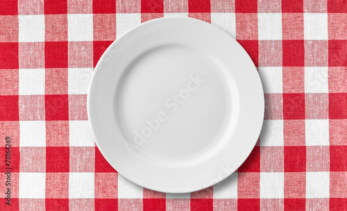 Empty white plate on checkered red tablecloth