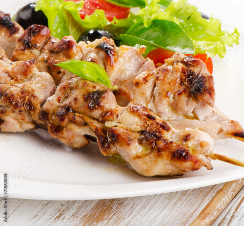 Grilled chicken kebab on a white plate