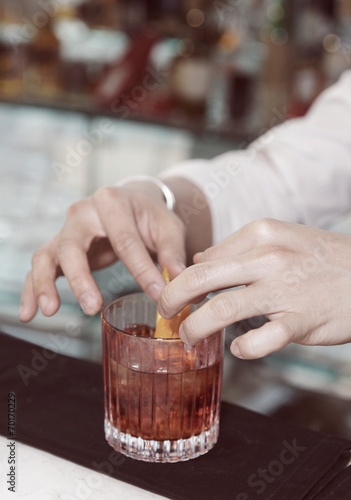 Barman is decorating drink with lemon zest