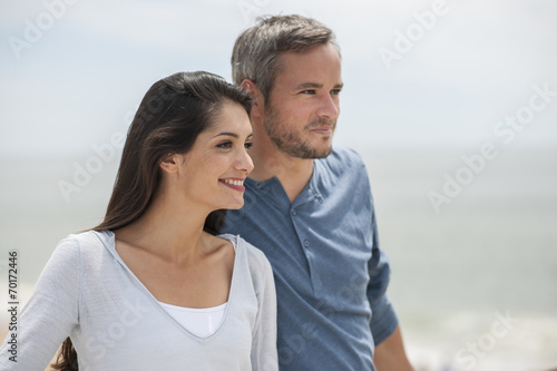 beautiful couple on the beach smiling and looking in the same di