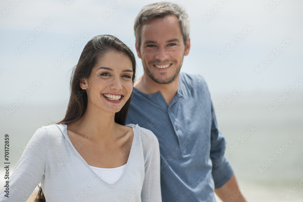 Obraz premium beautiful couple on the beach smiling and looking at camera