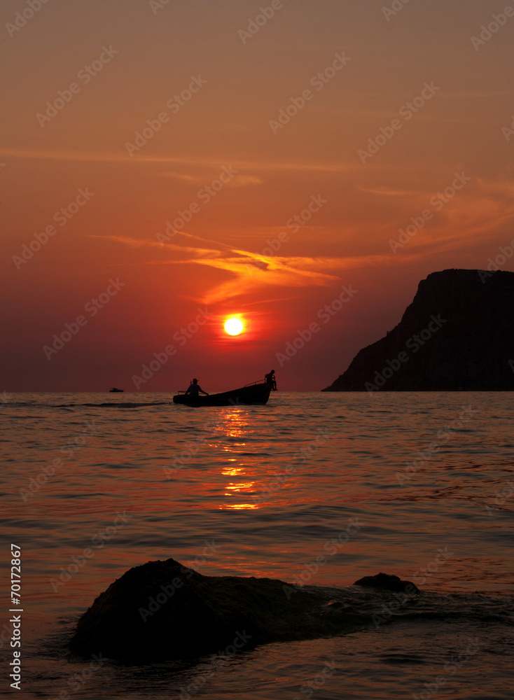 Two people in a boat at sunset