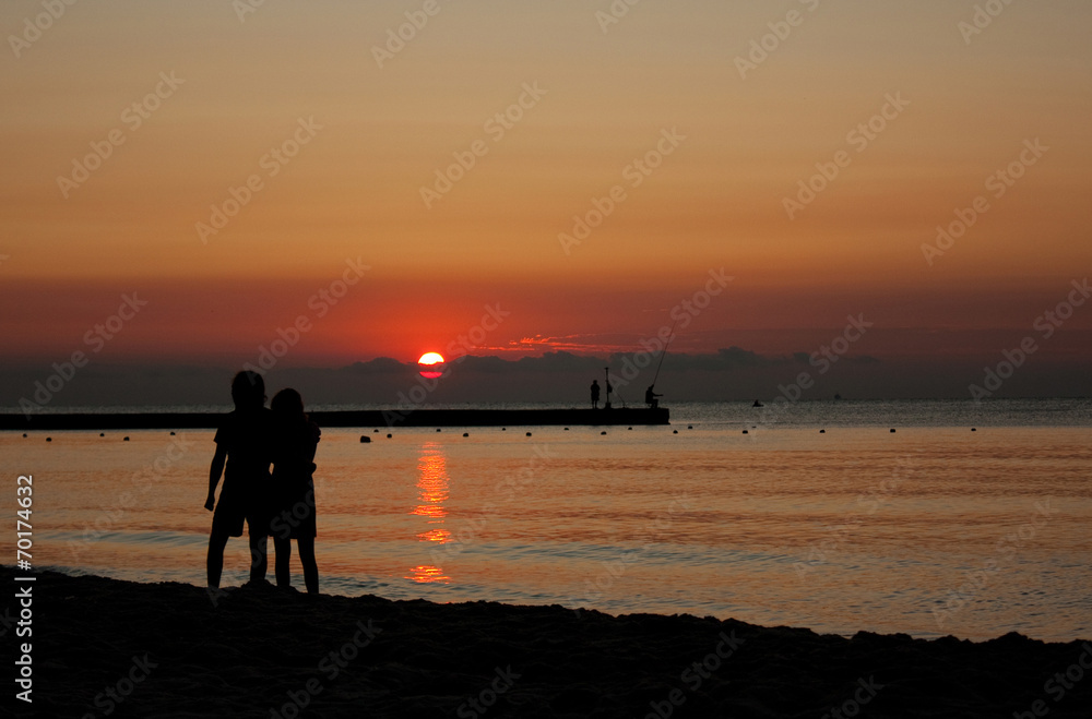 silhouettes of a couple at beach in sunlight