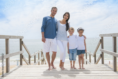 happy family standing on a wood pontoon in front of the sea in