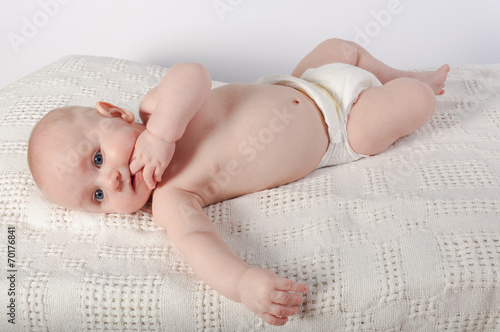 Teething baby resting on back chewing fingers