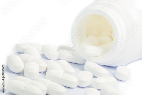 White Medical pills spilling out of a medicine bottle