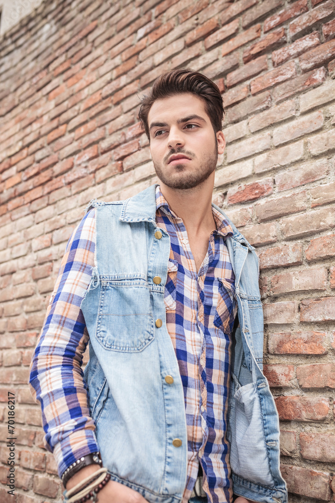 young casual man leaning on a brick wall young casual man leaning on a brick wall