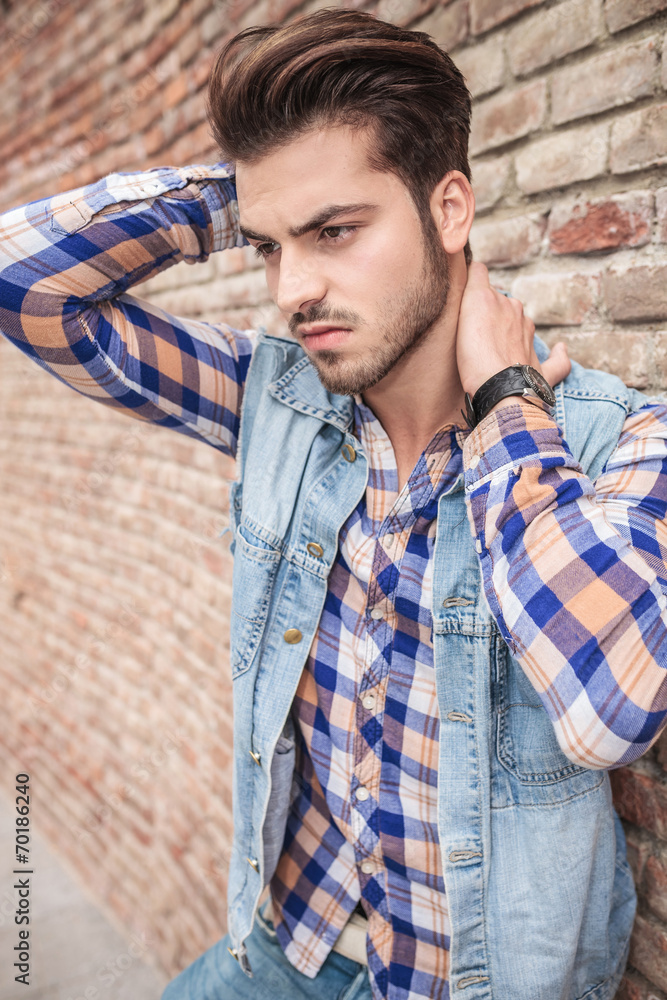 Obraz premium man leaning on wall holding his hand on his neck