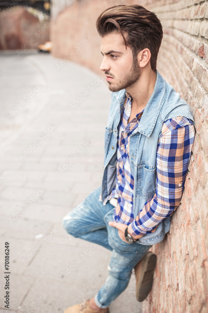 casual man leaning on a brick wal casual man leaning on a brick wal