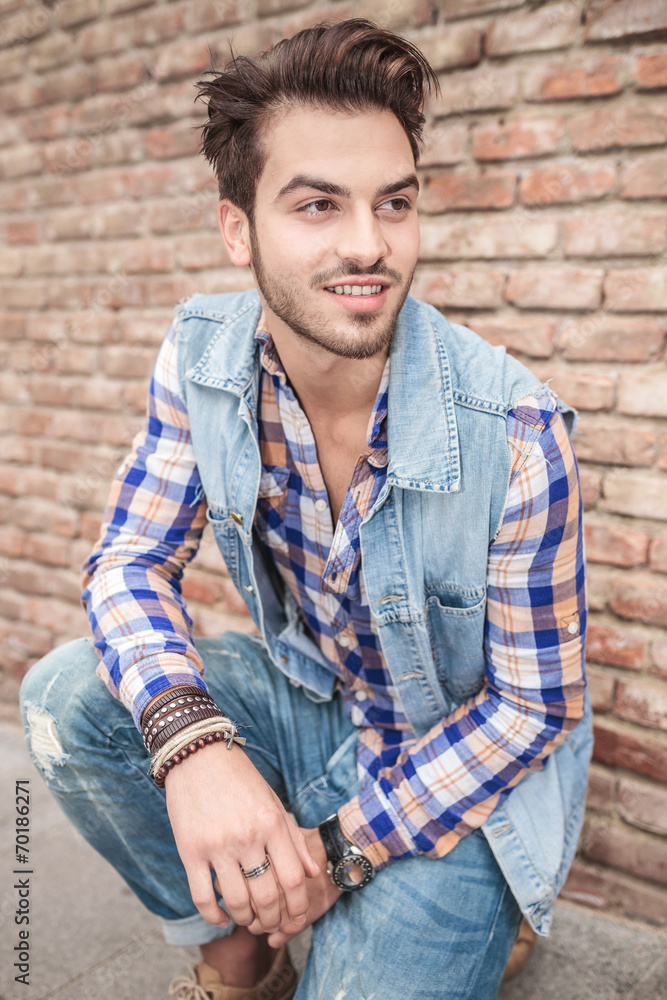 handsome man sitting near a brick wall handsome man sitting near a brick wall