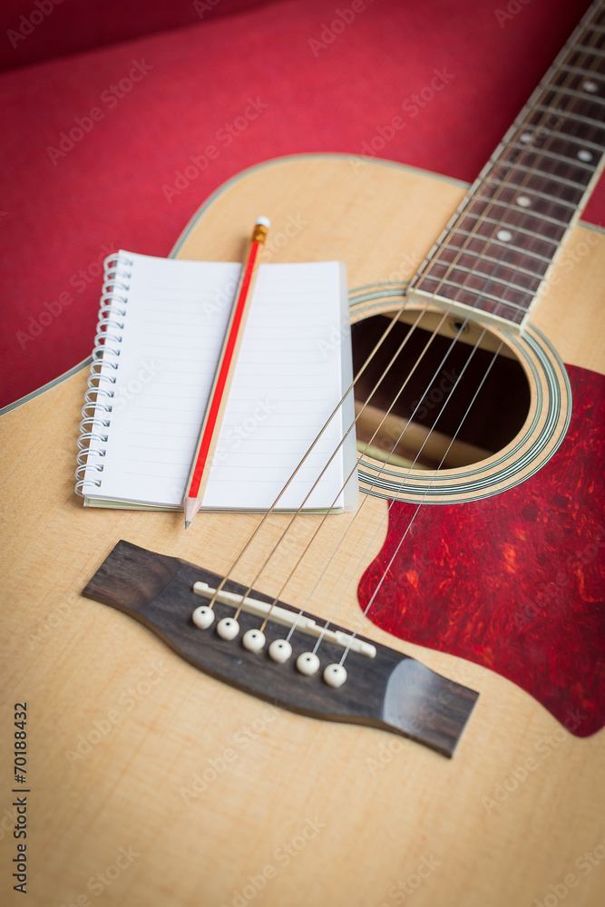 Fototapeta premium Notebook and pencil on guitar