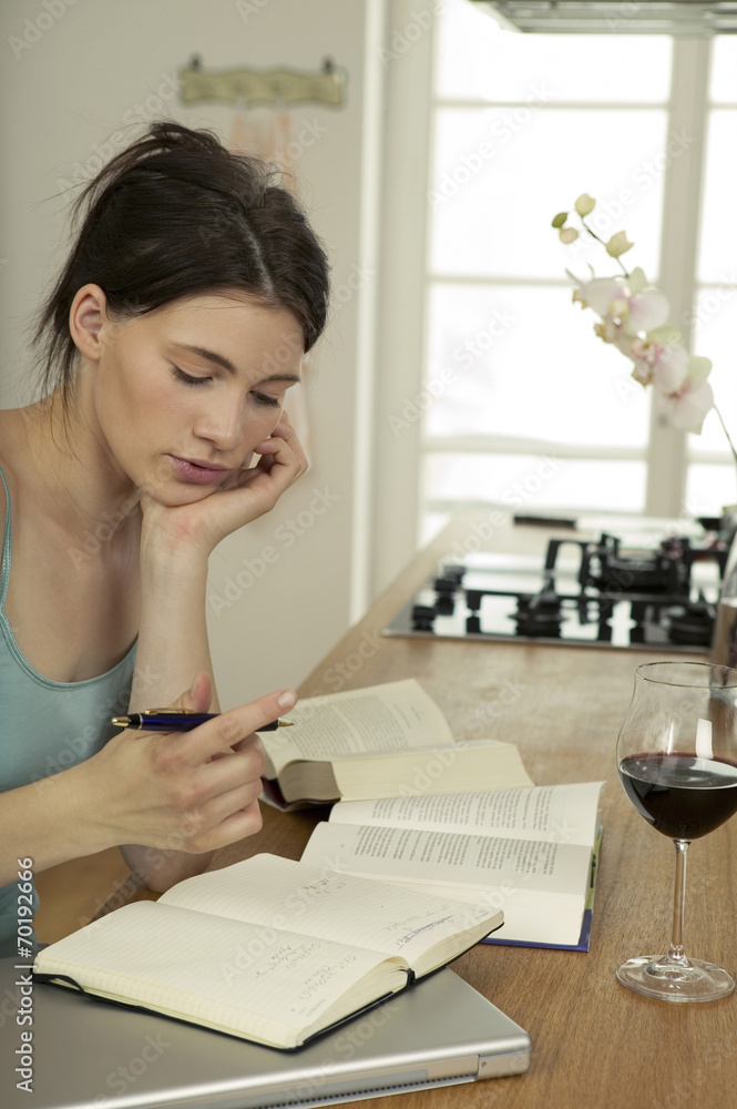Junge Frau mit Bücher in der Küche,die Hand am Kinn Junge Frau mit Bücher in der Küche,die Hand am Kinn