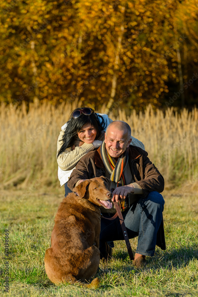 Fototapeta premium Cheerful couple with dog in autumn countryside