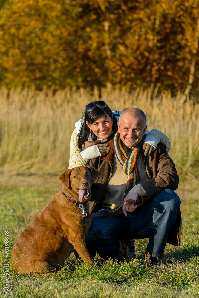 Cheerful couple with dog in autumn park