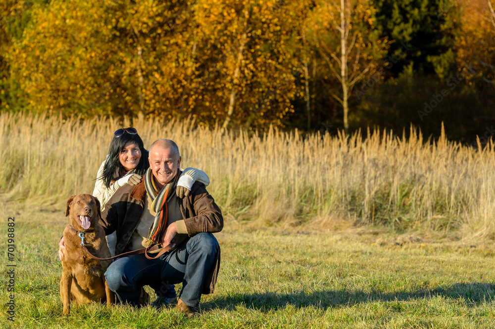 Fototapeta premium Cheerful couple with dog in autumn countryside