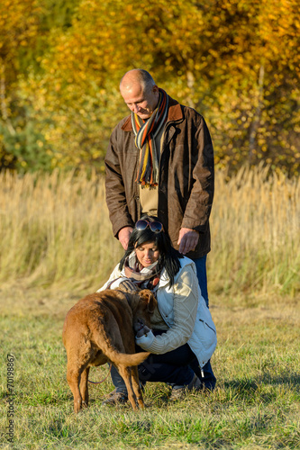 Couple playing with dog sunny autumn park