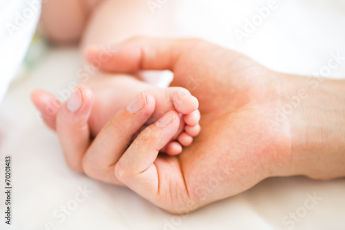 Father holding the foot of his new born son