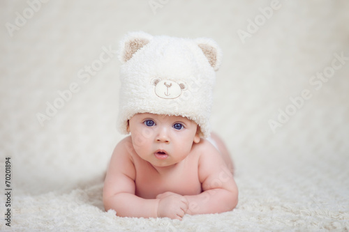 Baby lying on a soft bed cover with cap