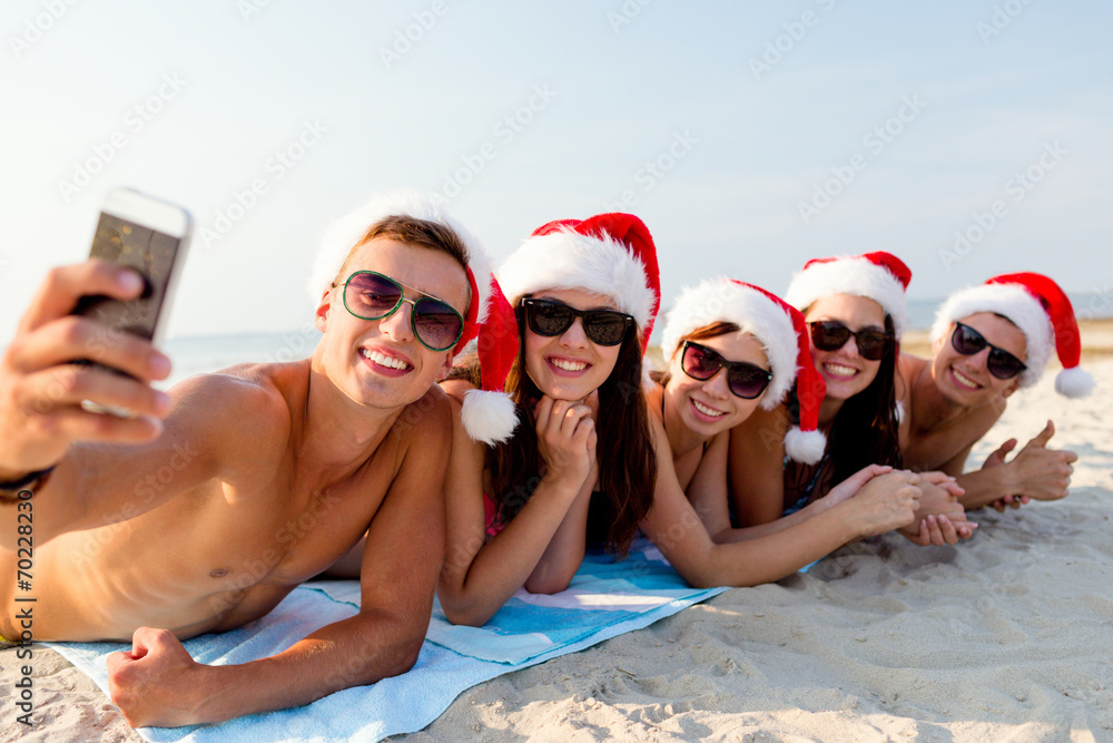 group of friends in santa hats with smartphone