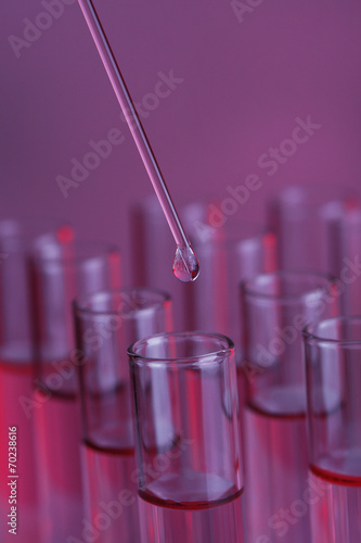 Test-tubes with blue liquid and stick on purple background