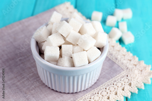 Refined sugar in color bowl on color wooden background