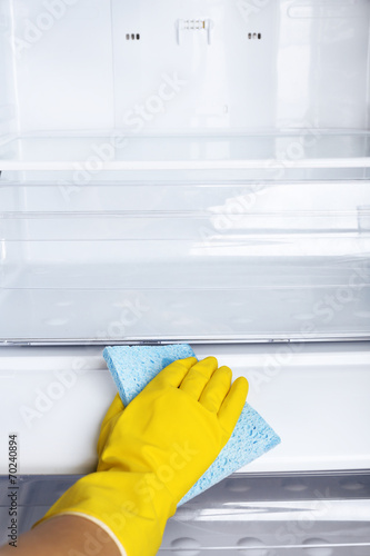 Woman's hand washing refrigerator with duster