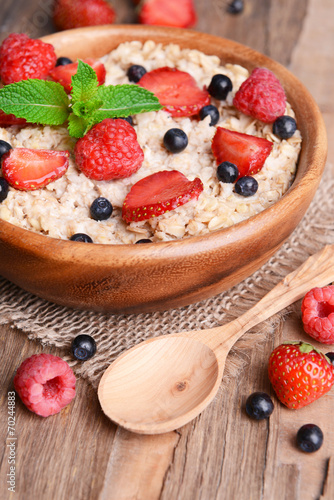 Tasty oatmeal with berries on table close-up