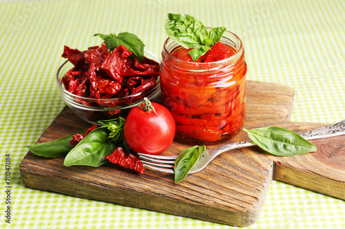 Sun dried tomatoes in glass jar, basil leaves