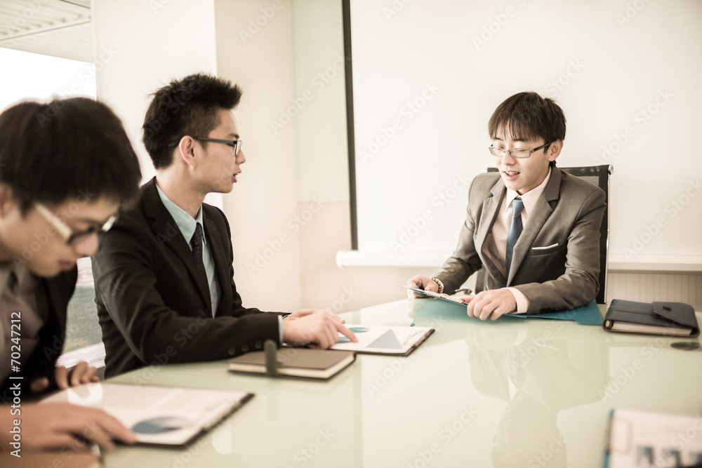 Young business people sitting in board room during meeting and d Young business people sitting in board room during meeting and d