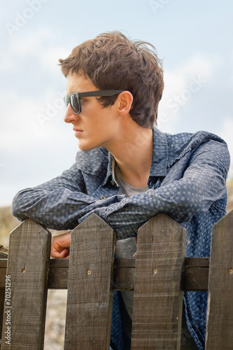 Hipster teenager with sunglasses over a fence