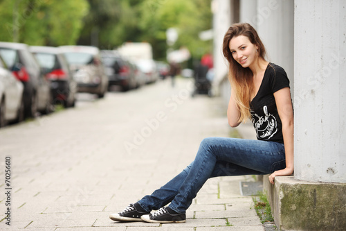 junge,hübsche Frau sitzt auf Mauer