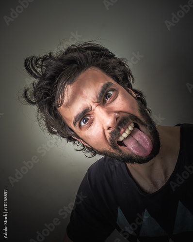 Young bearded and disheveled sticking out her tongue