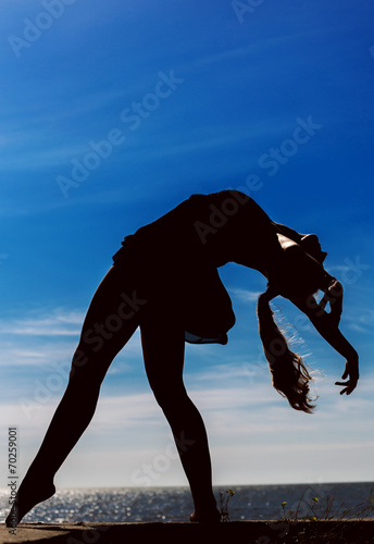 Girl dances on the beach at sunset. Natural light and darknesss.