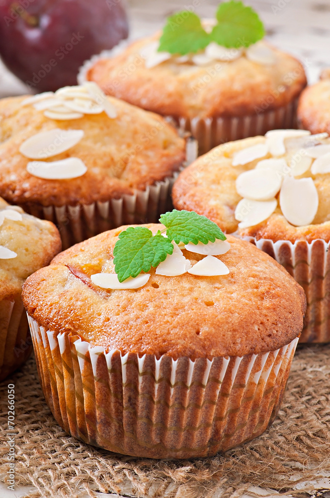 Muffins with plums and almond petals decorated with mint leaves Muffins with plums and almond petals decorated with mint leaves